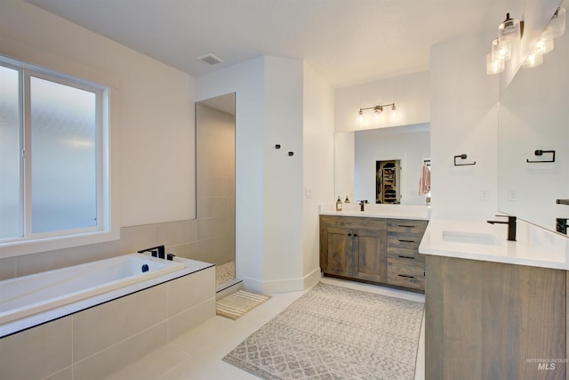 bathroom with tile patterned floors, vanity, and shower with separate bathtub