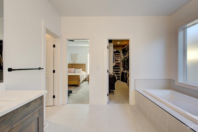 bathroom featuring tiled tub, a wealth of natural light, tile patterned flooring, and vanity