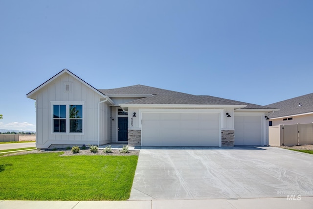 view of front of home featuring fence, driveway, a garage, a front lawn, and board and batten siding