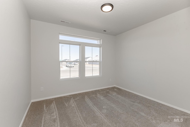 carpeted empty room featuring baseboards and visible vents
