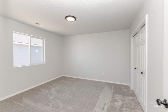 unfurnished bedroom with carpet, a closet, baseboards, and visible vents