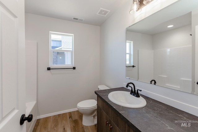 full bath with toilet, vanity, visible vents, and wood finished floors