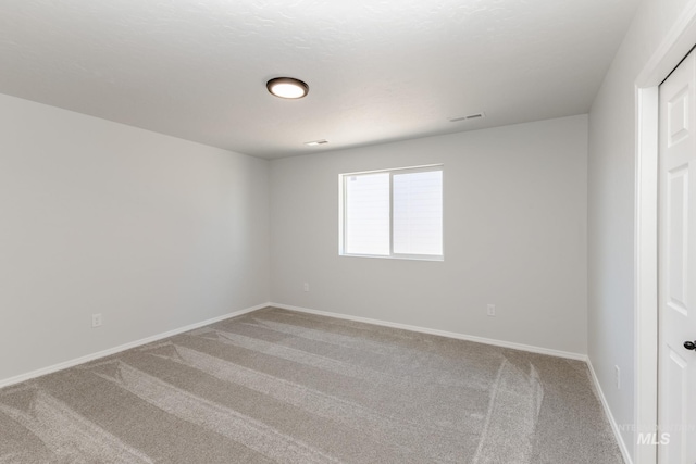 carpeted spare room featuring baseboards and visible vents