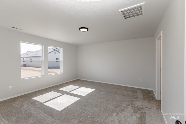 carpeted spare room with baseboards and visible vents