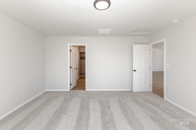 unfurnished bedroom featuring carpet flooring, visible vents, baseboards, and a walk in closet