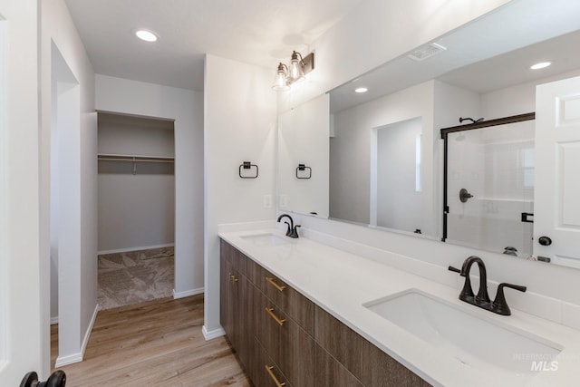bathroom featuring a stall shower, recessed lighting, a sink, and wood finished floors