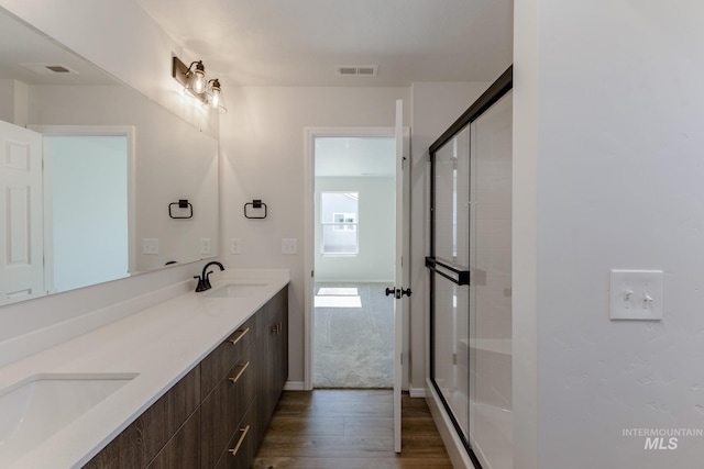 full bath with a stall shower, visible vents, a sink, and wood finished floors