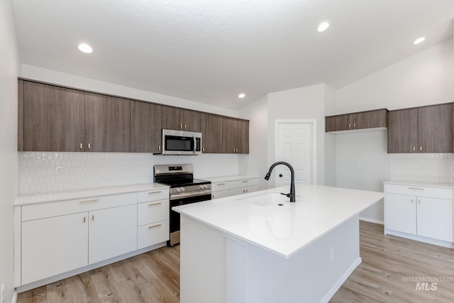 kitchen with backsplash, stainless steel appliances, light wood-style flooring, and a sink