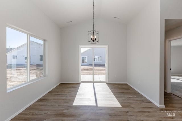 unfurnished dining area featuring vaulted ceiling, a notable chandelier, visible vents, and wood finished floors