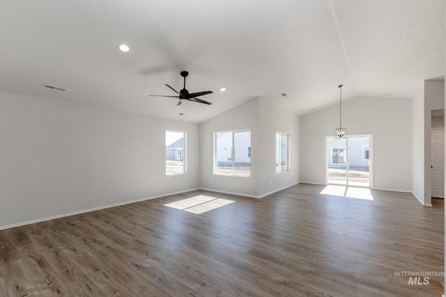 unfurnished living room featuring plenty of natural light, visible vents, lofted ceiling, and ceiling fan with notable chandelier