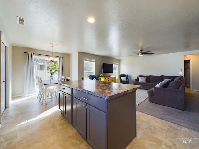 5122 Allentown St, Caldwell, ID 83605 - kitchen with a kitchen island, open floor plan, a ceiling fan, a textured ceiling, and a chandelier