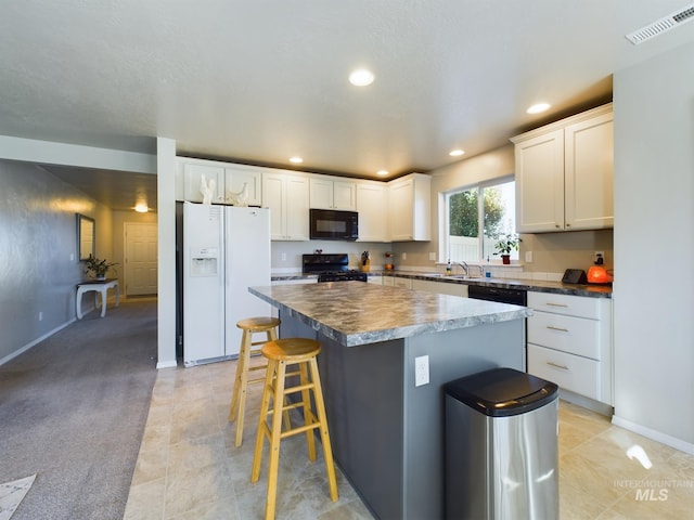 5122 Allentown St, Caldwell, ID 83605 - kitchen featuring black appliances, a center island, a breakfast bar, dark countertops, and white cabinets