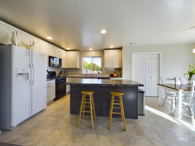 5122 Allentown St, Caldwell, ID 83605 - kitchen featuring black appliances, dark countertops, a kitchen breakfast bar, a center island, and white cabinets