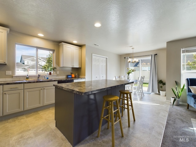 5122 Allentown St, Caldwell, ID 83605 - kitchen with dark countertops, a chandelier, a kitchen island, a breakfast bar area, and recessed lighting