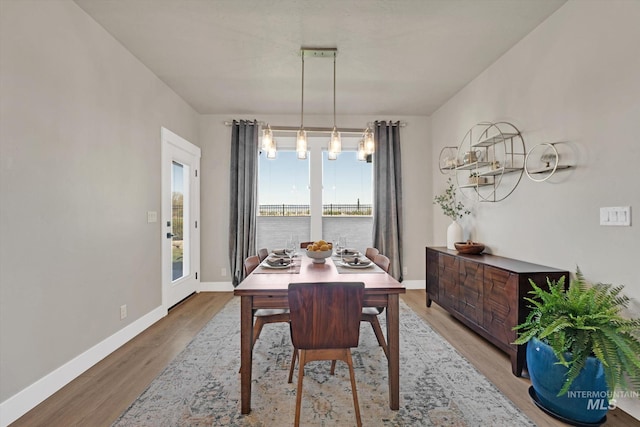 dining space with baseboards, wood finished floors, and a chandelier