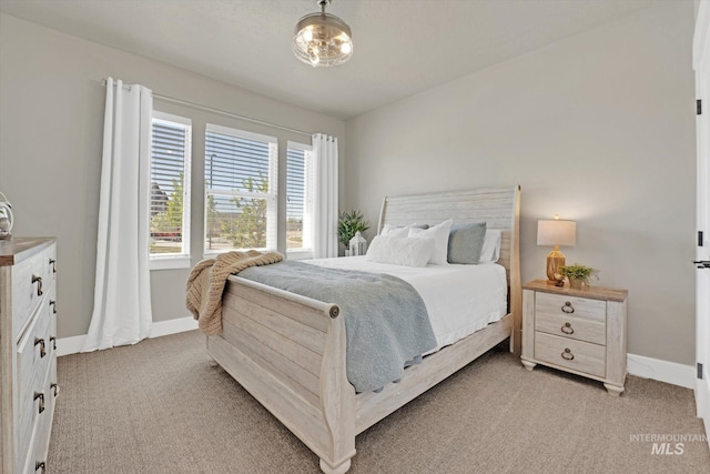 bedroom with light colored carpet and baseboards