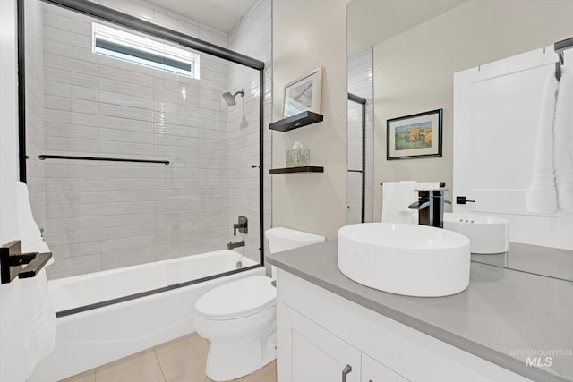 full bath with tile patterned flooring, combined bath / shower with glass door, toilet, and vanity