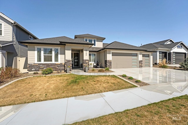 view of front of property featuring an attached garage, stone siding, a front yard, and driveway