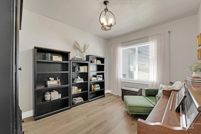 living area featuring baseboards, a notable chandelier, and light wood-style floors