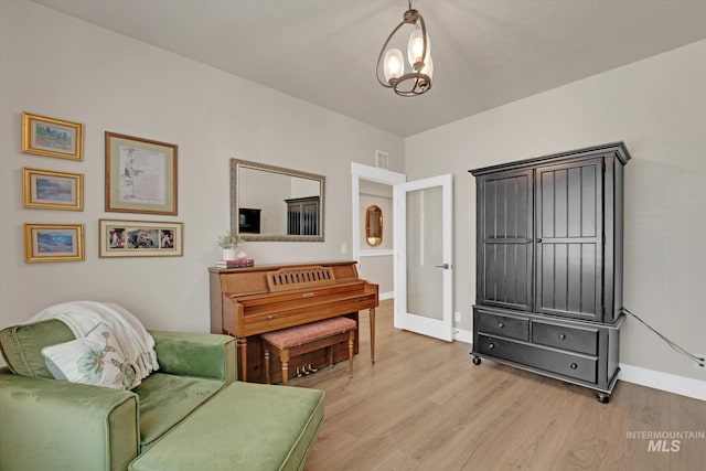 living area featuring light wood-type flooring, visible vents, and baseboards