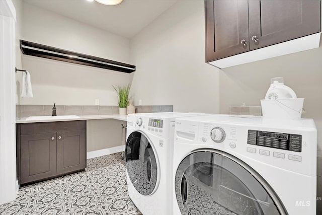 clothes washing area featuring baseboards, cabinet space, washer and clothes dryer, and a sink