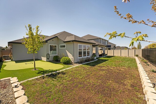 rear view of property featuring a fenced backyard and a lawn