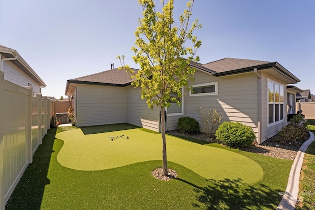 rear view of house featuring roof with shingles and a fenced backyard