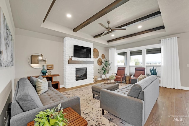 living room with light wood-type flooring, baseboards, recessed lighting, a ceiling fan, and a fireplace