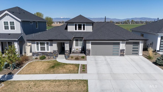 view of front of home featuring an attached garage, a shingled roof, concrete driveway, and a mountain view