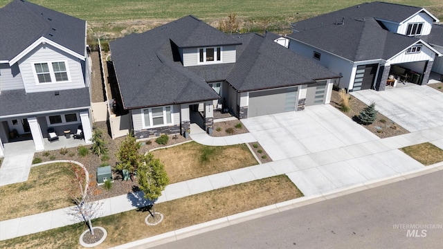 view of front of home featuring a garage, a shingled roof, stone siding, and concrete driveway
