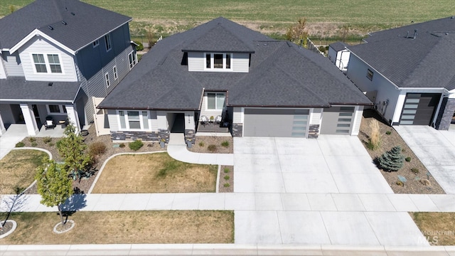 view of front of house featuring an attached garage, driveway, roof with shingles, and stone siding