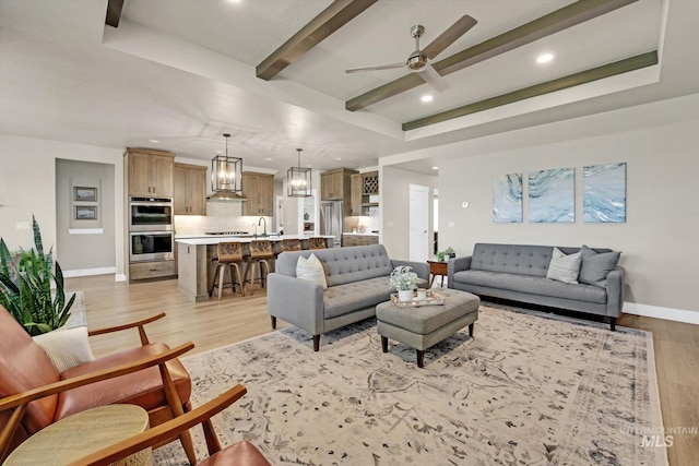 living area featuring recessed lighting, light wood finished floors, a ceiling fan, beamed ceiling, and baseboards