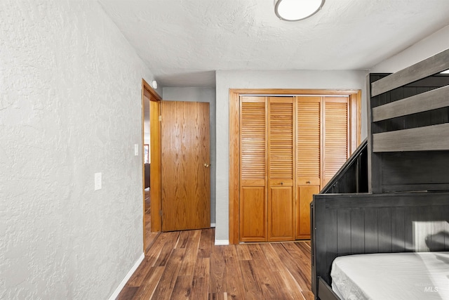 bedroom with hardwood / wood-style floors, a textured ceiling, and a closet