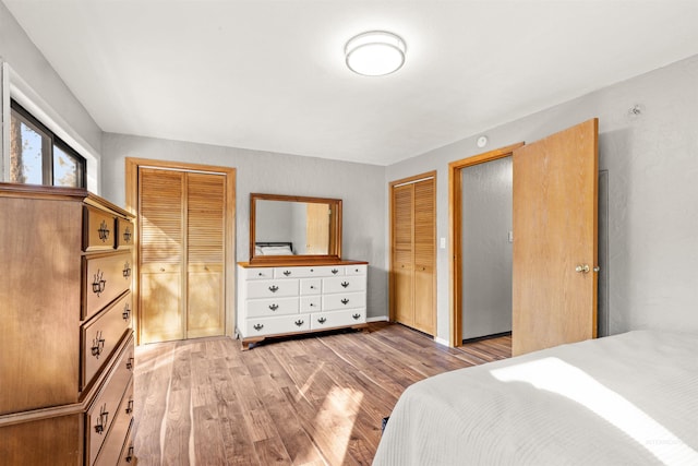 bedroom with two closets and light hardwood / wood-style flooring