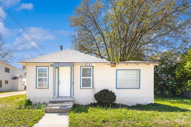 bungalow-style house with roof with shingles and a front lawn
