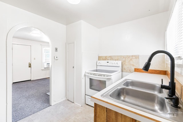 kitchen with light colored carpet, a sink, light countertops, arched walkways, and white electric stove