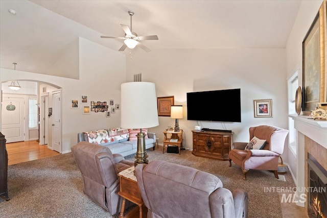 562 Castle Rock Ave, Middleton, ID 83644 - carpeted living area featuring a ceiling fan, arched walkways, a tile fireplace, and high vaulted ceiling