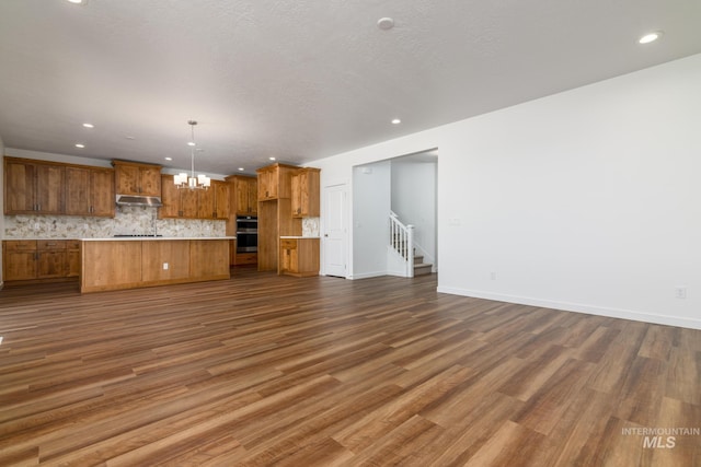 unfurnished living room featuring a chandelier, a textured ceiling, and dark hardwood / wood-style floors