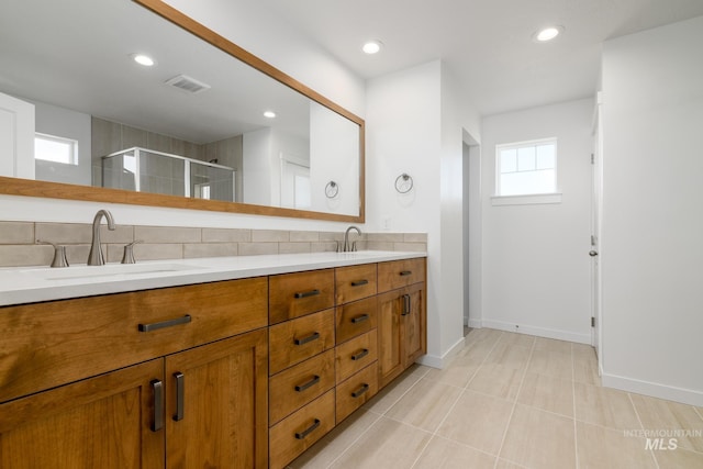 bathroom featuring backsplash, vanity, and a shower with shower door