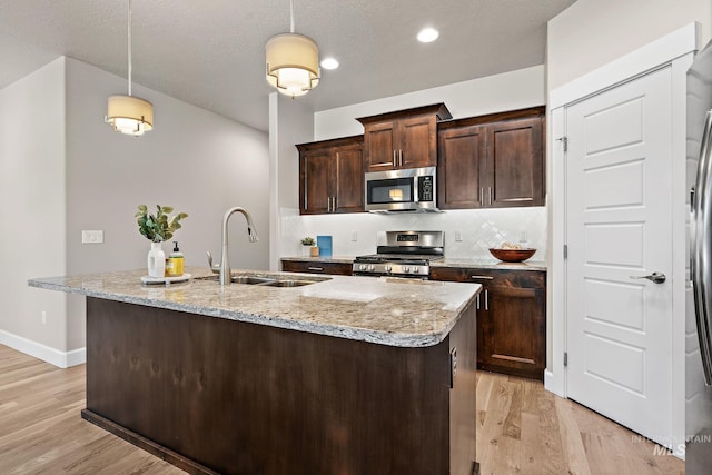 1457 Summerheights, Meridian, ID 83646 - kitchen with light wood-style floors, a sink, appliances with stainless steel finishes, backsplash, and hanging light fixtures