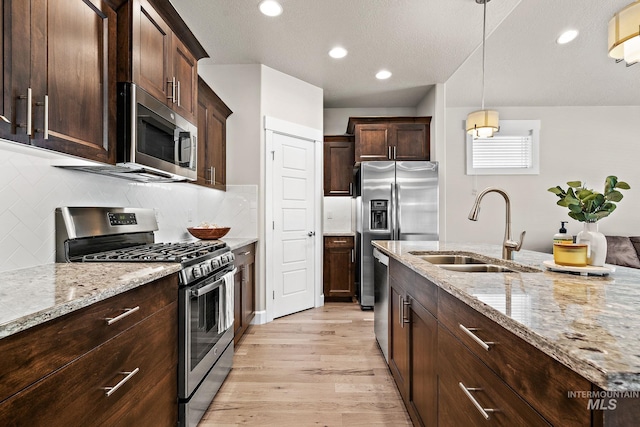 1457 Summerheights, Meridian, ID 83646 - kitchen featuring dark brown cabinetry, appliances with stainless steel finishes, light stone countertops, a sink, and light wood-style flooring