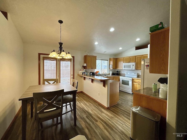 kitchen with dark wood-type flooring, lofted ceiling, hanging light fixtures, kitchen peninsula, and white appliances