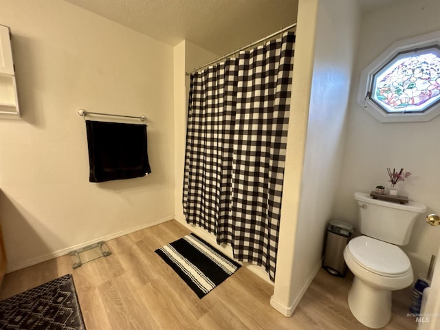 bathroom featuring hardwood / wood-style flooring, a shower with curtain, and toilet