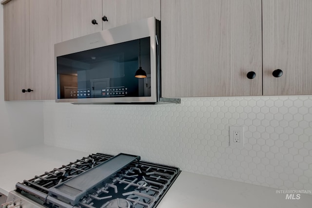 room details featuring gas range, light brown cabinetry, and tasteful backsplash