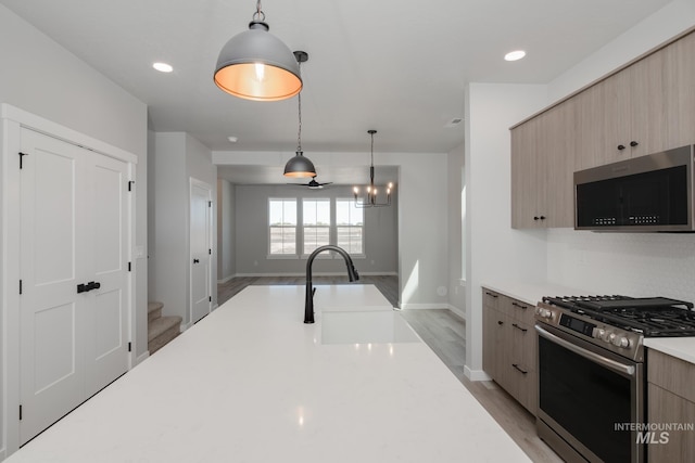 kitchen with light hardwood / wood-style floors, stainless steel appliances, hanging light fixtures, sink, and a chandelier