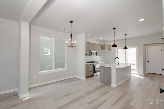 kitchen with light hardwood / wood-style floors, a kitchen island with sink, pendant lighting, appliances with stainless steel finishes, and light brown cabinetry