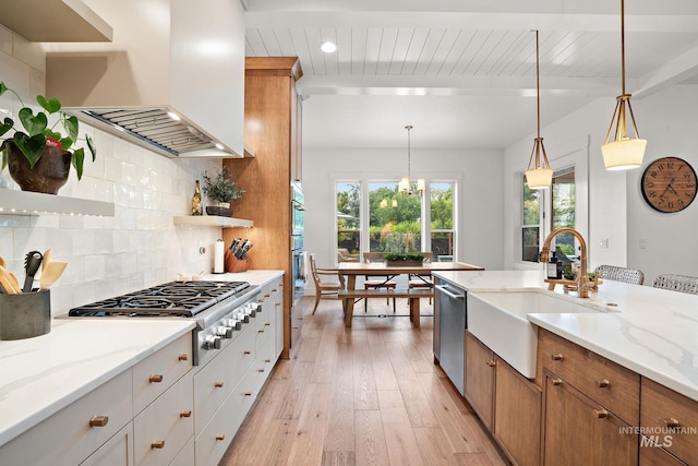 kitchen with white cabinetry, stainless steel appliances, light stone counters, range hood, and backsplash