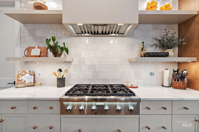 kitchen featuring light stone countertops, tasteful backsplash, and exhaust hood