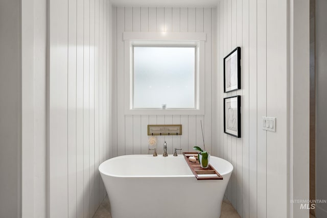 bathroom featuring a bath and wood walls