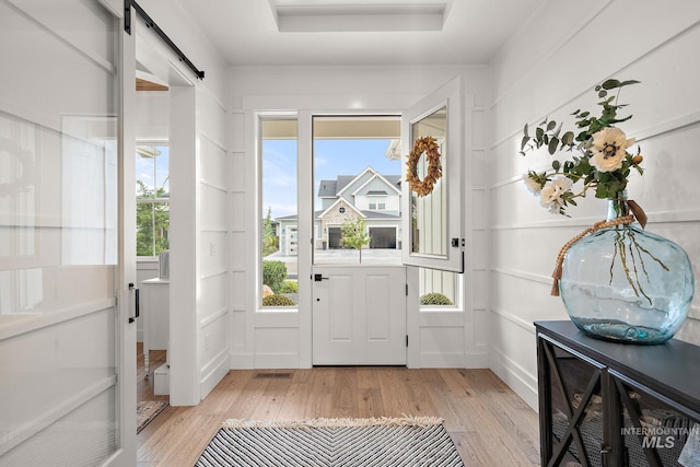 entryway with light wood-type flooring and a barn door